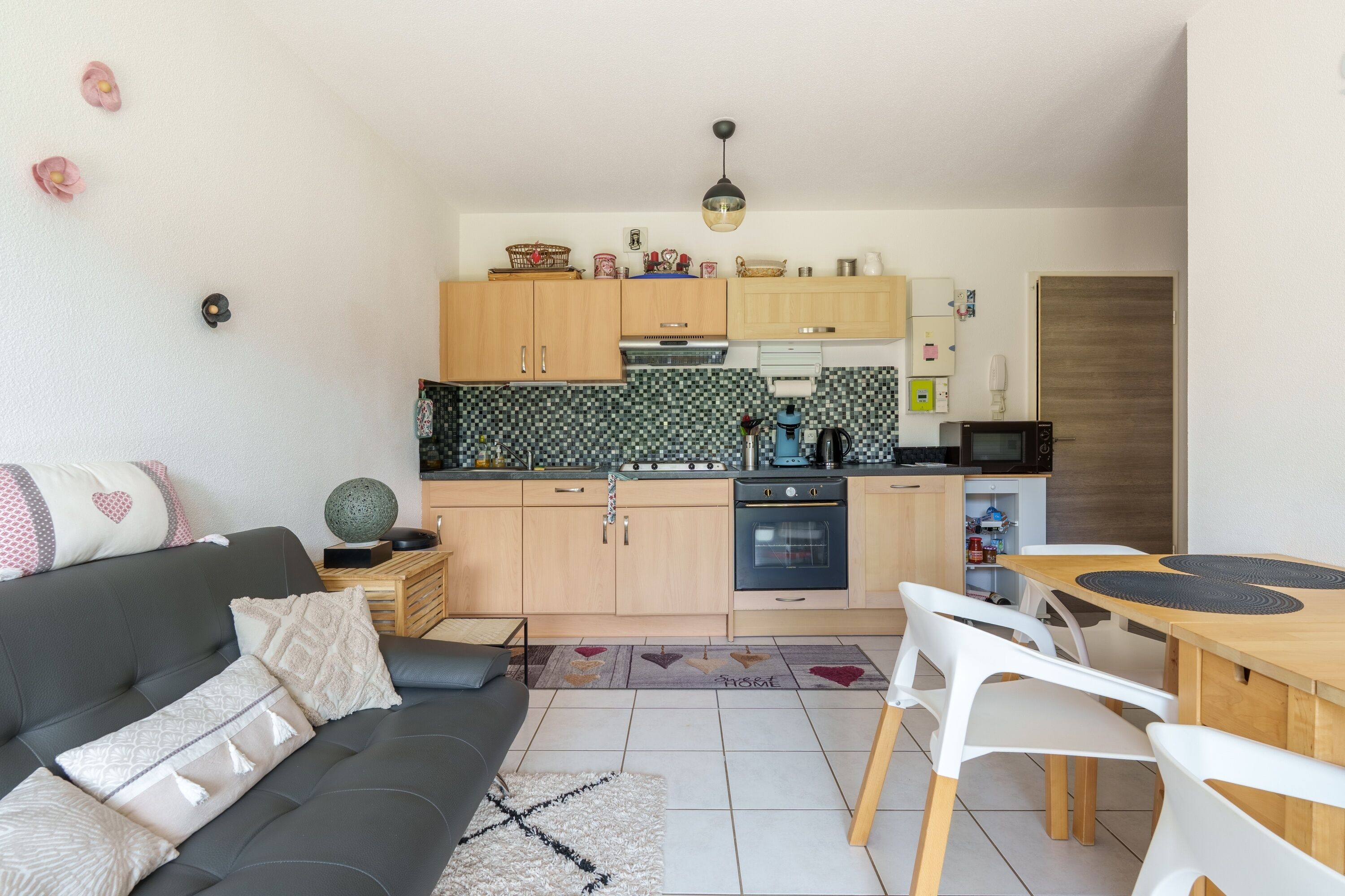A compact living space with a kitchenette, a dining area, and a sofa.