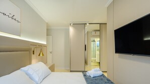 Quarto de hotel com cama, televisão e banheiro visível por uma porta aberta.