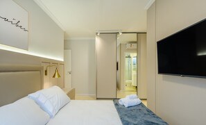 A hotel room with a bed, a TV, and a bathroom visible through an open door. - Apto prox. do mar em Balneário Piçarras PDG0202 (Picarras)
