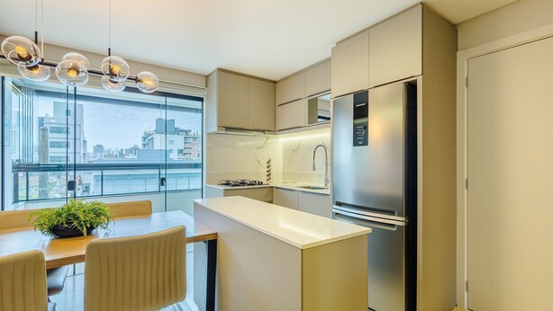 Uma cozinha moderna com geladeira embutida, fogão a gás e uma janela grande com vista para a cidade.