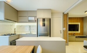 A modern kitchen with a central island, built-in appliances, and a sleek design. - Apto prox. do mar em Balneário Piçarras PDG0202 (Picarras)