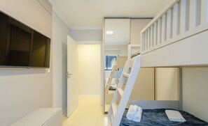 A modern hotel room with a bunk bed, a flat-screen TV, a wardrobe, and a neatly made bed. - Apto prox. do mar em Balneário Piçarras PDG0202 (Picarras)
