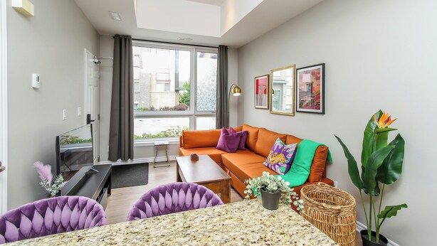 Ein modernes Wohnzimmer mit einer Couch, einem Couchtisch und zwei violetten Sesseln.
