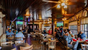 A restaurant with wooden tables and chairs, ceiling fans, and large windows. - EV charger & desk+monitor! 2-1 in the Heights. FULLY fenced in. 5 min to d-town (Houston)
