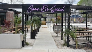 A covered outdoor seating area with a neon sign reading "Come Be Social". - EV charger & desk+monitor! 2-1 in the Heights. FULLY fenced in. 5 min to d-town (Houston)