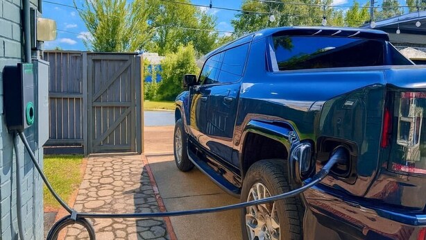 A blue pickup truck parked in a driveway with a hose connected to a water spigot on the side of a building. - EV charger & desk+monitor! 2-1 in the Heights. FULLY fenced in. 5 min to d-town (Houston)