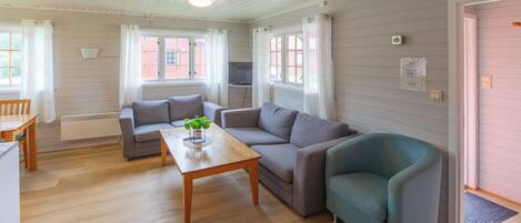 A cozy living room with a wooden table, two sofas, and a teal armchair.