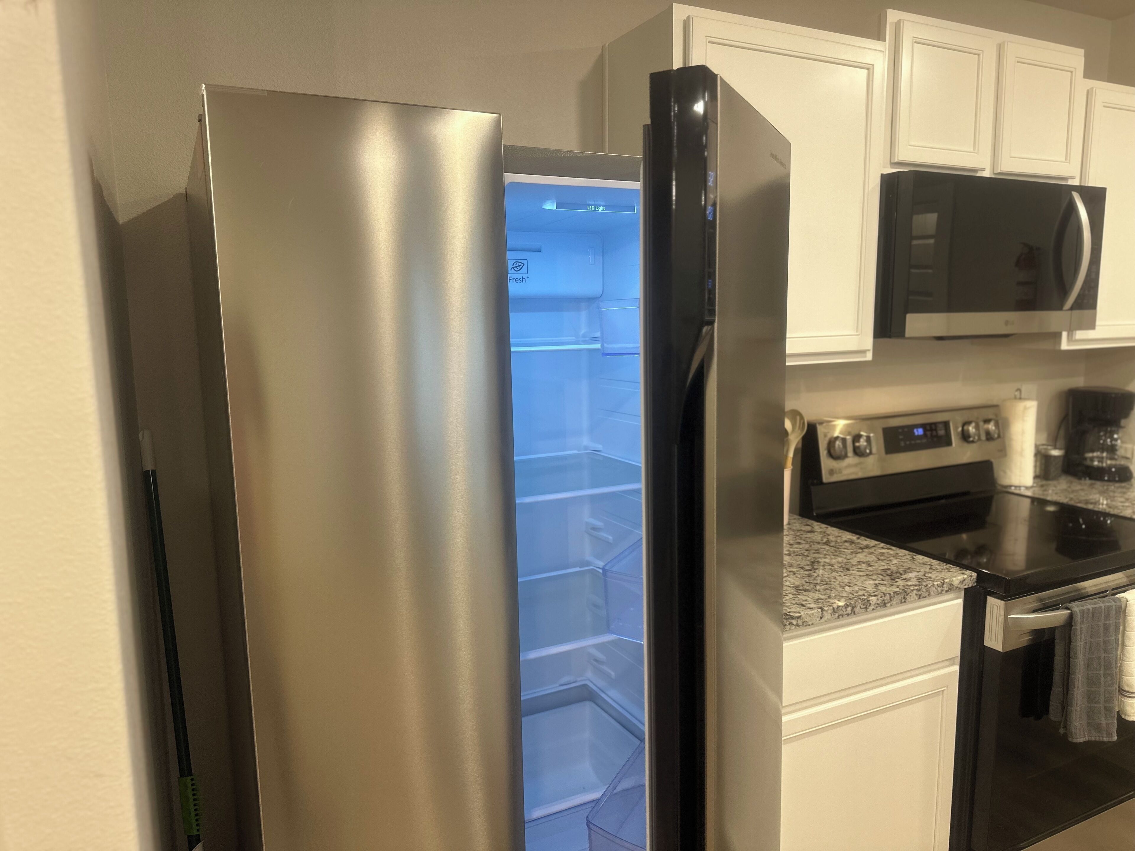 A stainless steel refrigerator with a freezer compartment, a microwave above it, and a stove below.
