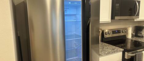 A stainless steel refrigerator with a freezer compartment, a microwave above it, and a stove below.