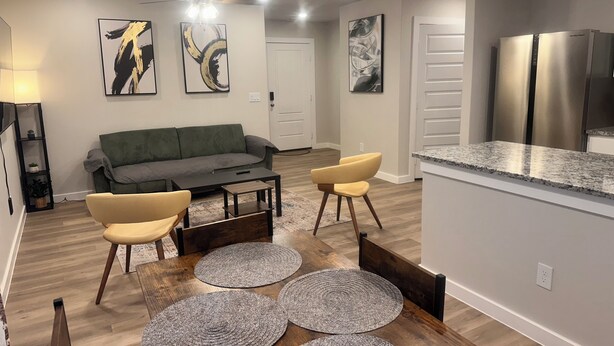 A modern living room with a grey sofa, two yellow armchairs, a wooden coffee table, and a dining area with a wooden table and four grey placemats. - 6 Beds,3-bedroom Charming home in Odessa (Odessa)
