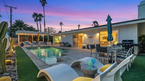A modern outdoor pool area with lounge chairs, a dining table, and a barbecue grill. - Palm Paradise offers a private 3BR retreat with a saltwater pool, fire pit, BBQ, and mountain views. Just minutes from downtown, this stylish getaway is perfect for families or friends seeking relaxation and Palm Springs charm. (Palm Springs)