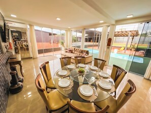 A dining area with a glass table set for six, surrounded by chairs. - Clube Relax & Lazer (Foz do Iguaçu)