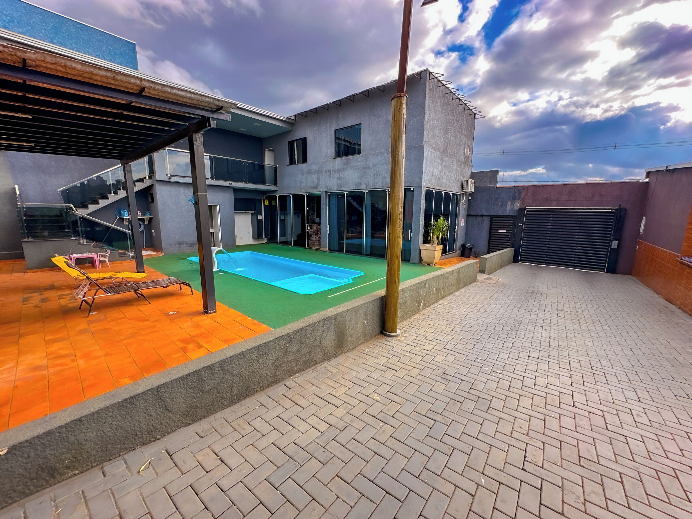 A modern building with a swimming pool, a covered patio, and a staircase leading to an upper level.