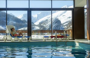A poolside area with lounge chairs and a view of snow-covered mountains. - Fitness, swimming pool, sauna, hammam, balcony, parking, tv, ski locker, 90m², Valloire (Valloire)
