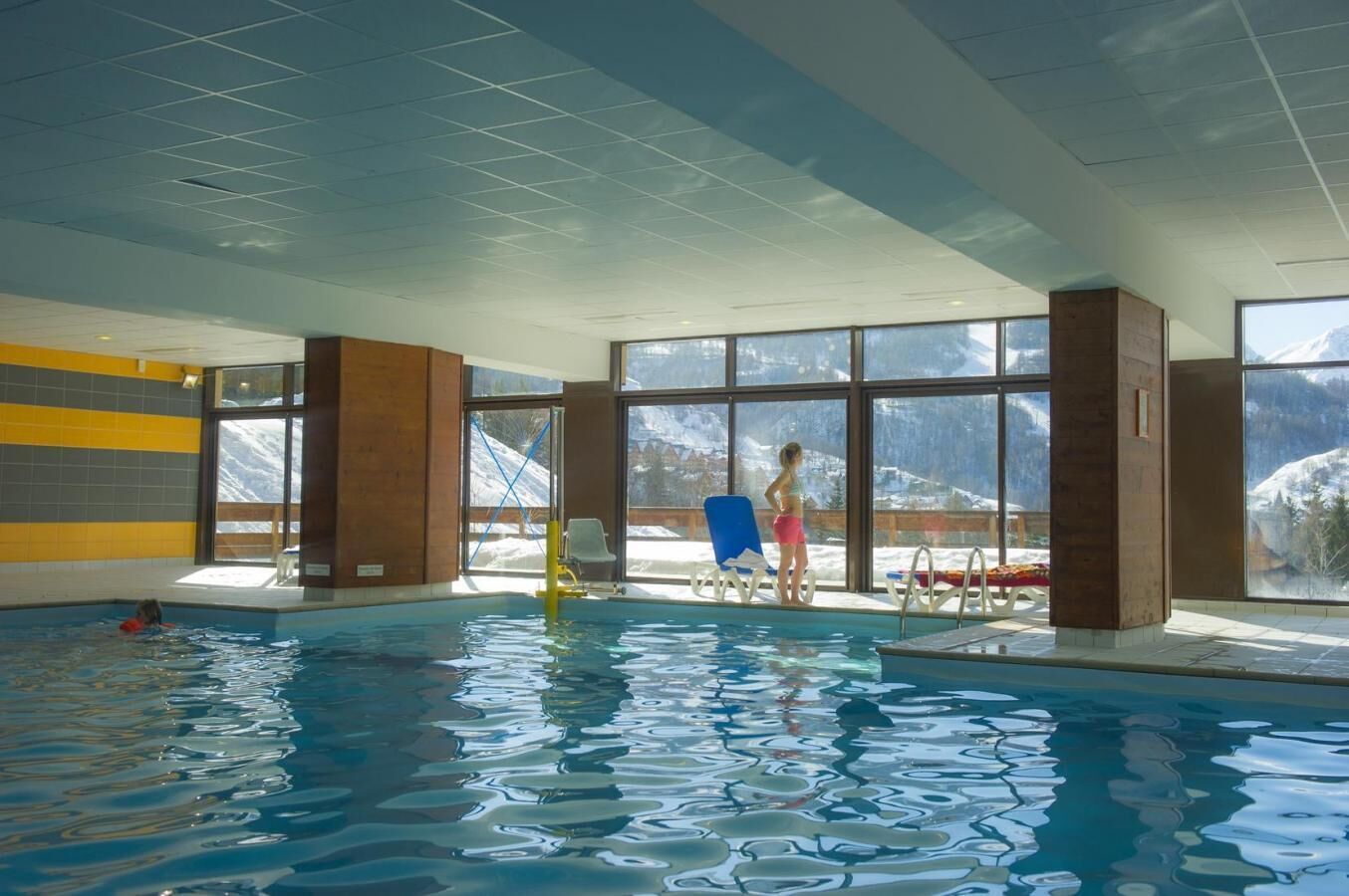 An indoor swimming pool with clear windows offering mountain views.