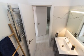 A bathroom with a white sink, mirror, and towel rack.