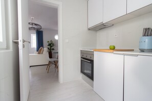 Une cuisine moderne avec des armoires blanches, un four encastré et un plan de travail en bois.