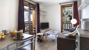 A modern living room with a sofa, coffee table, TV, and dining area with breakfast items. - 200m from resort center, terrace, balcony, tv, 35-50m², Les 2 Alpes (Les Deux Alpes)