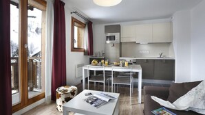 Ein kompakter Wohnbereich mit Essplatz, Küchenzeile und einer Couch.