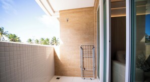 A modern bathroom with a shower, a towel rack, and a view of palm trees outside. - Chaves do Atlântico (Cabedelo)