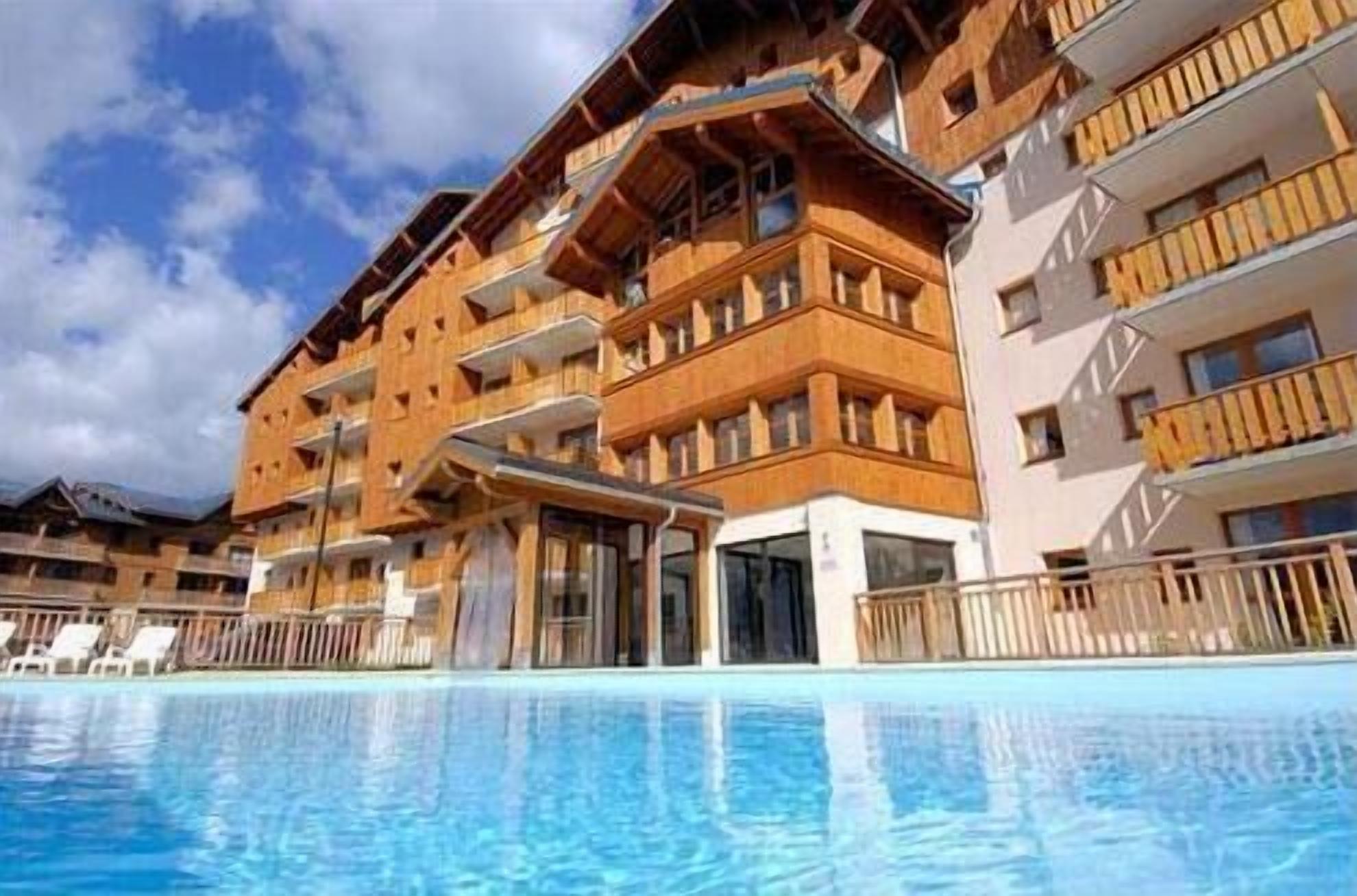 A multi-story hotel with balconies and a swimming pool in the foreground.
