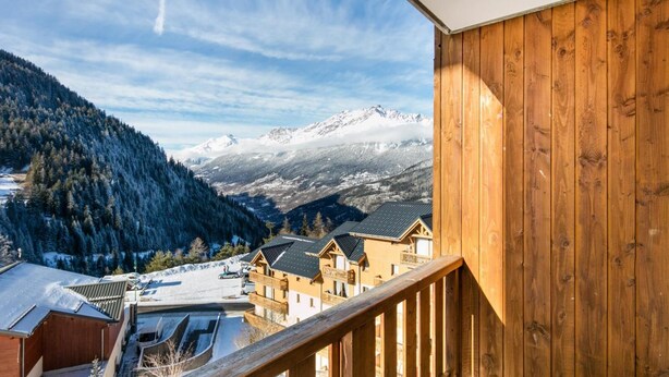 A wooden balcony overlooking a snowy mountain landscape with chalet-style buildings. - Wifi, ski-in/ski-out & foot of the slopes, swimming pool, sauna, tv, ski locker, 43m², Valfréjus (Valfréjus)