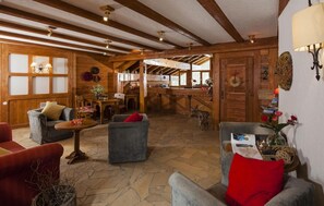 A cozy, rustic interior with wooden beams, stone flooring, and comfortable seating areas.