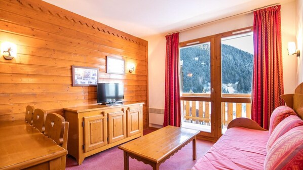 A cozy room with wooden walls, a wooden table, a bed, and a TV on a cabinet. - Wifi, 300m from resort center, swimming pool, sauna, tv, ski locker, 40m², Valfréjus (Valfréjus)