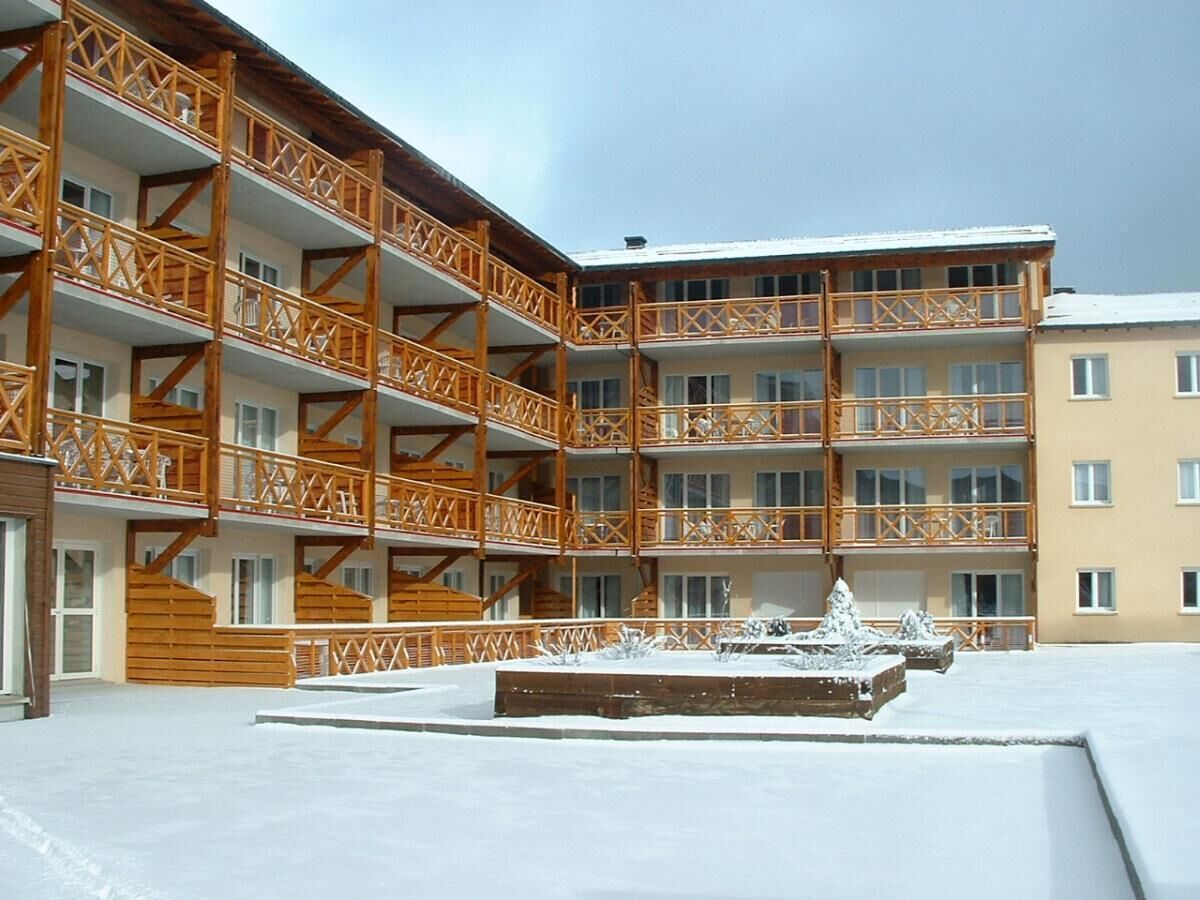 A multi-story building with wooden balconies and a snow-covered courtyard.