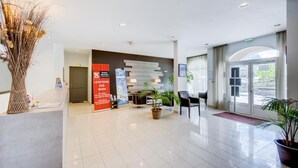 Un hall d’hôtel moderne avec un comptoir d’accueil, un espace salon et une grande fenêtre.