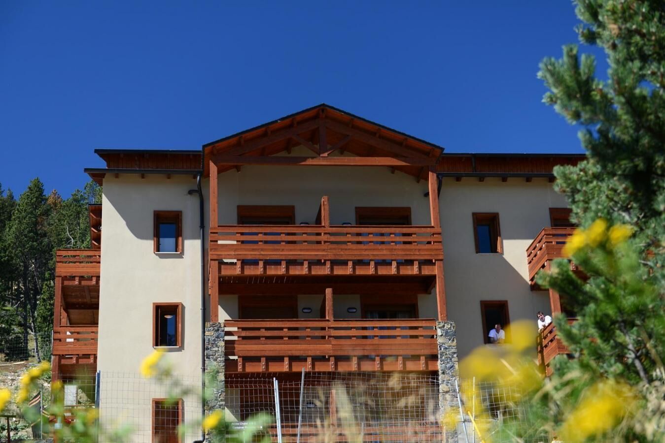 Un edifici de diversos pisos amb un balcó de fusta i una base de pedra.