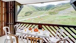 A dining area with a table set for two, overlooking a mountainous landscape with a railway track.