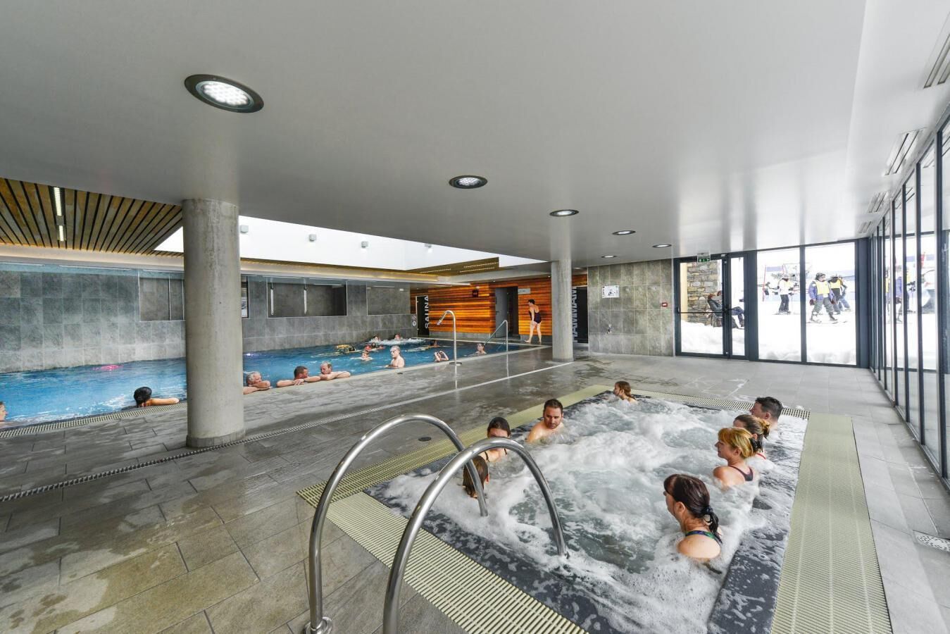 Un área de piscina interior moderna con varias piscinas y un jacuzzi.