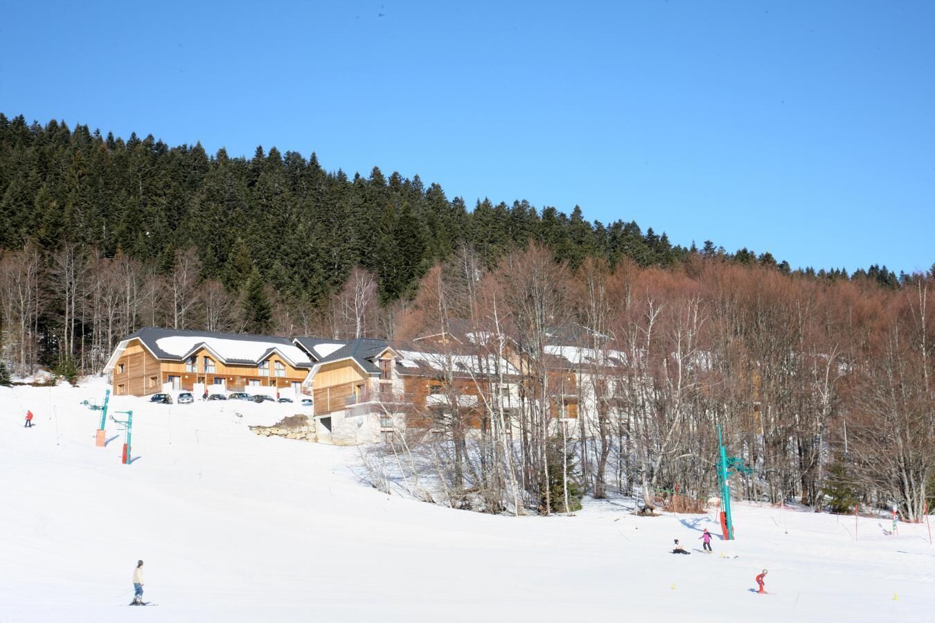 A ski resort with wooden cabins and a snowy landscape.