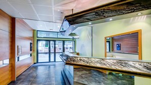 A modern lobby with a marble reception desk, glass doors leading outside, and a ceiling with a perforated design. - 100m from ski lifts, tv, ski locker, 62m², Luchon-Superbagnères (Bagnères-de-Luchon)