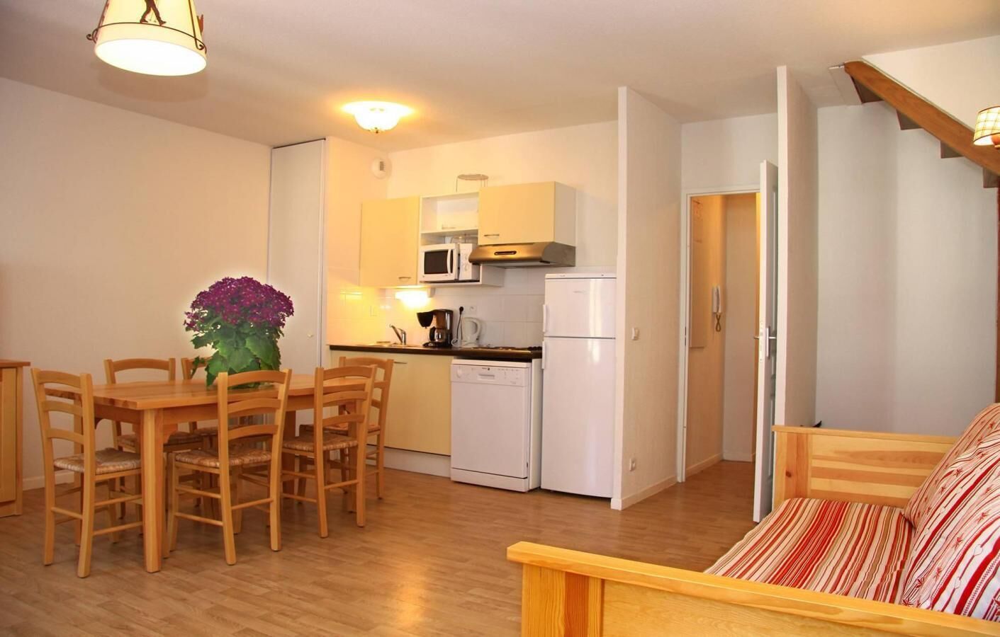 Un espace de vie compact comprenant un coin repas, une kitchenette et un lit.