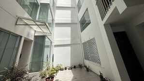A modern building with multiple floors, large windows, and potted plants.