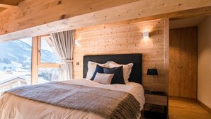A bedroom with a large bed, wooden walls, a nightstand, and a window with curtains. - Chalet, fitness, sauna, hammam, terrace, balcony, fireplace or stove, tv, 125m², Praz sur Arly (Praz-sur-Arly)