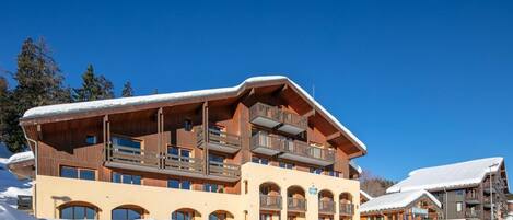 A multi-story hotel with balconies, a stone facade, and snow-covered surroundings.