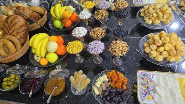 Un bufé con diversas opciones de comida, incluyendo frutas, frutos secos y pastelería.
