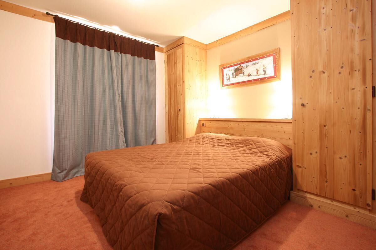 Quarto com cabeceira de madeira, colcha acolchoada e quadro pendurado na parede.