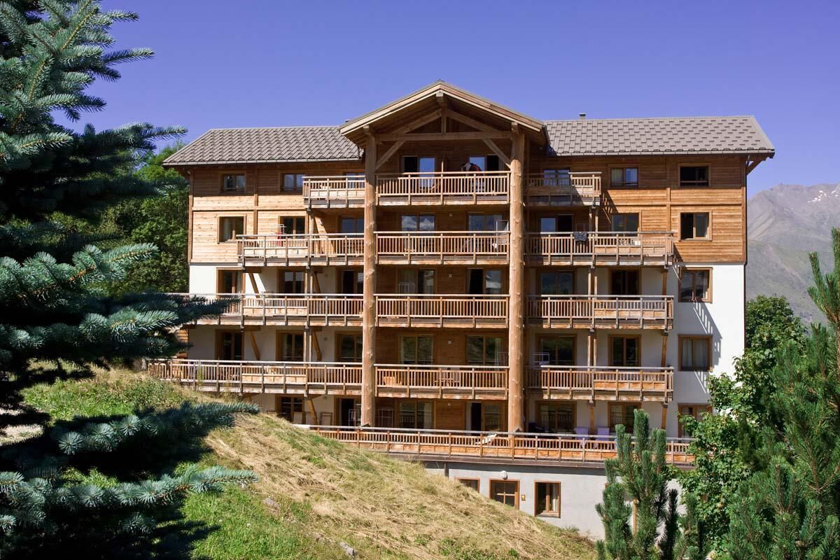 Un edificio de madera de varios pisos con balcones, con montañas al fondo.