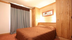 Un dormitorio con cabecera de madera, colcha acolchada y un cuadro en la pared.