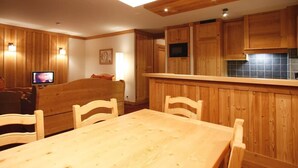 Un intérieur chaleureux en bois, avec un coin repas, des meubles de rangement en bois et un téléviseur.