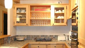 Eine Küche mit Holzausstattung, einer gefliesten Rückwand und einem Edelstahlbackofen.