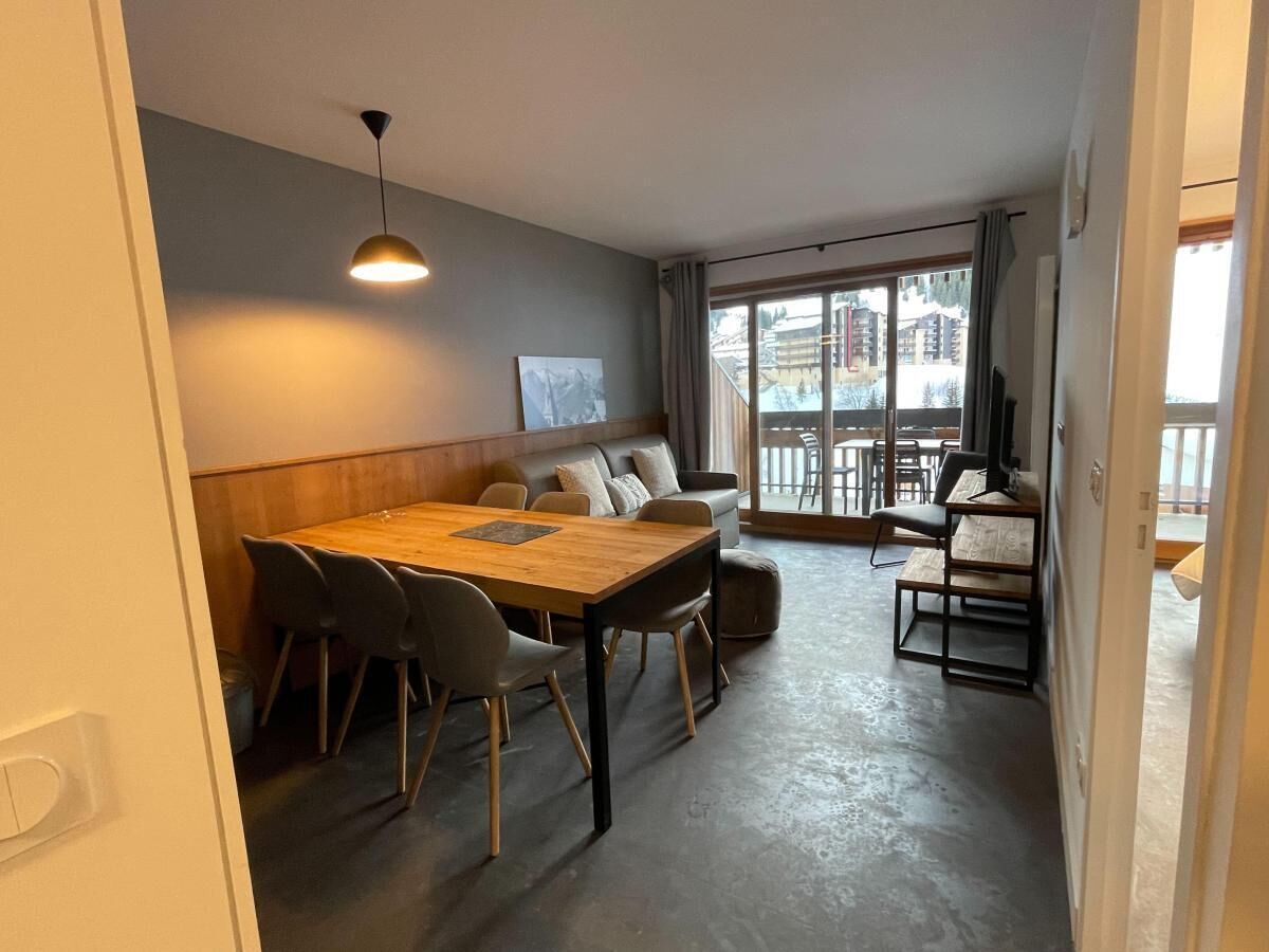 Un'area pranzo con un tavolo e sedie in legno, un divano e una TV.