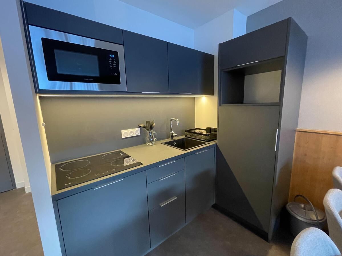 A compact kitchen with a built-in microwave, stove, and sink.