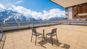 A terrace with two chairs and a table, overlooking a mountainous landscape.