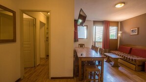 A cozy room with a wooden dining table, benches, and a sofa.