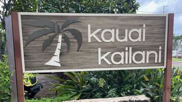 Une enseigne en bois avec le texte « Kauai Kailani » et une illustration représentant un palmier.